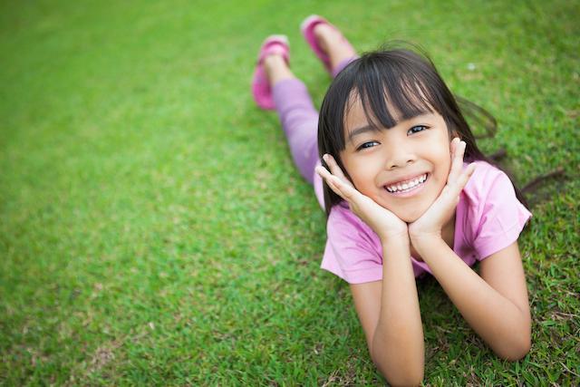 young girl laying in grassy field I 62526 dentist