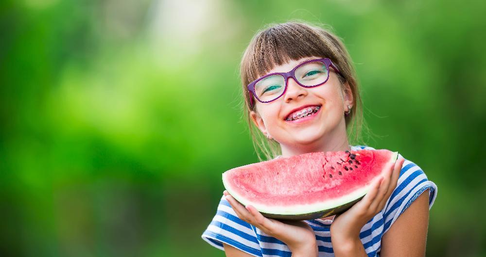 Girl with braces holding a watermelon | Orthodontics Decatur IL