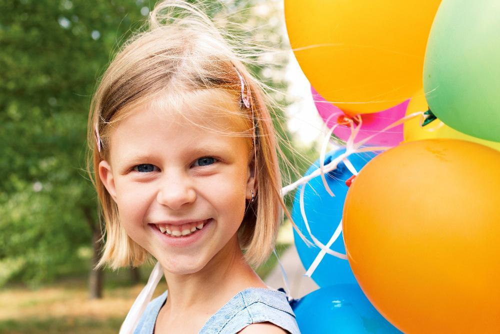 young girl smiling with balloon l dental cleanings decatur il