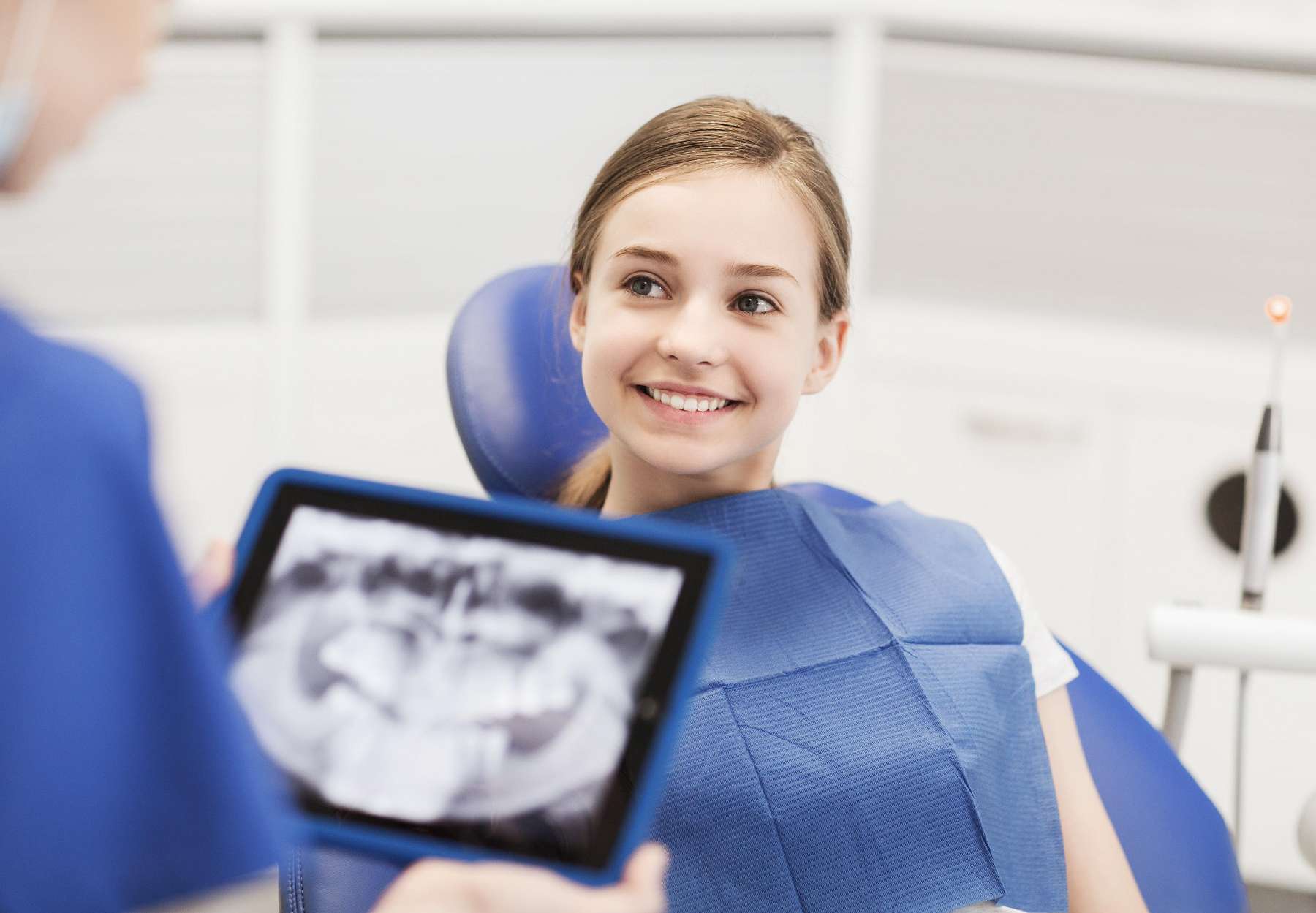 Kid smiling as the dentist observes the X-ray picture of her teeth in Decatur, IL