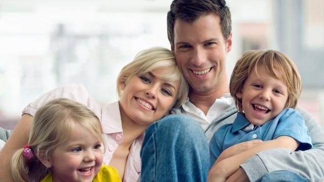 Young family of four smiling & hugging after family dentistry at Jerger Pediatric Dentistry